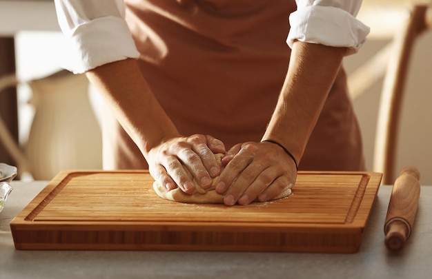 Hands preparing dough on wooden board